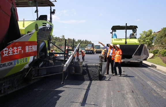 攤鋪機(jī)、壓路機(jī)等設(shè)備緊張有序運(yùn)行，高達(dá)170℃的瀝青混合料炙烤著公路人